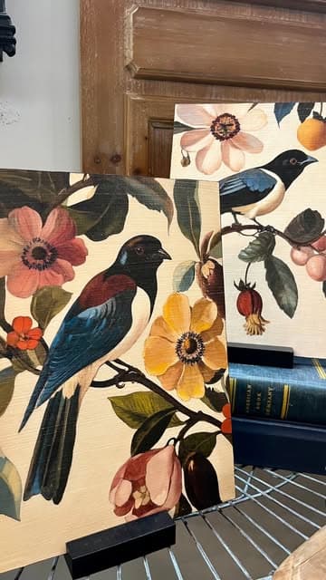 Botanical bird canvases in rust, amber and blue propped on a shelf
